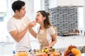 Couple together in kitchen room, Young asian man holding vegetables to woman