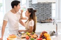 Couple together in kitchen room, Young asian woman holding vegetables to man Royalty Free Stock Photo