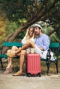 Couple of tourist listening music with a tablet sitting in a bench in the park Royalty Free Stock Photo