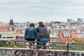 Couple of tourist watching cityscape of Prague on sunny day. The detail view of modern and old part of town with traditional red