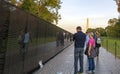 a couple of tourists contemplating the Vietnam Memorial Wall with the George Washington monument in the background Royalty Free Stock Photo