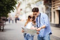 Young Couple of tourists is exploring new city together. Smiling and look at the map on the city street Royalty Free Stock Photo