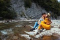 Couple of tourists kissing by mountain river enjoying landscape. Travelers sitting on rock. Summer vacation Royalty Free Stock Photo
