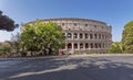 A couple of tourists looking at the Colosseum ancient amphitheater under the clear blue sky.