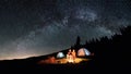 Couple tourists near campfire and tents under night sky full of stars and milky way Royalty Free Stock Photo