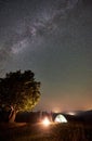 Couple tourists at night camp in mountains under starry sky Royalty Free Stock Photo