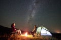 Couple tourists at night camp in mountains under starry sky Royalty Free Stock Photo