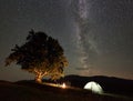 Couple tourists at night camp in mountains under starry sky Royalty Free Stock Photo