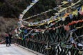 Couple tourists with tear colorful Tibetan prayer flags waving and swaddled with bridge over frozen river at Thangu and Chopta.