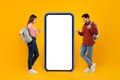 Couple Of Tourists Using Cellphones Near Big Smartphone, Yellow Background Royalty Free Stock Photo