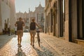 A couple or tourists are walking on the cobblestone road towards the sunset in Krakow city, with Glowny Rynek or Main city square