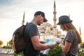 A couple of tourists a young man and a pretty woman look at the map next to the world-famous Blue Mosque also called Royalty Free Stock Photo