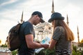 A couple of tourists a young man and a pretty woman look at the map next to the world-famous Blue Mosque also called Royalty Free Stock Photo