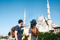 A couple of tourists a young man and a pretty woman stand next to the world-famous Blue Mosque also called Sultanahmet