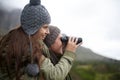 Couple, travel and binoculars on mountains for journey, adventure and hiking or explore together in winter. Happy man Royalty Free Stock Photo