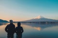 Couple traveler standing and looking Beautiful Mount Fuji with snow capped in the morning sunrise at Lake kawaguchiko, Japan. Royalty Free Stock Photo