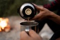 Couple of travelers drink coffee. Man pouring tea from thermos. Picnic at sea beach. Woman holding metal cup with Royalty Free Stock Photo