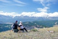 Couple travelers Man and Woman sitting on cliff relaxing mountains and enjoying valley view. Royalty Free Stock Photo
