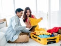 Couple travelers packing trip. Young Asian woman trying on clothes, yellow dress and man holding tablet for travel information. Royalty Free Stock Photo