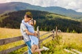 Couple of travelers walking by fence in Carpathian mountains enjoying landscape. People hug. Summer vacation Royalty Free Stock Photo