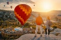 Couple travelers watches colorful balloons flying on an early sunny morning in Cappadocia.Turkey.