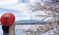 Couple traveller with a red umbrella and walking over the bridge with Fuji mountain and Sakura flower background Royalty Free Stock Photo