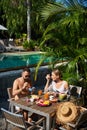 Couple of travellers eating food in hotel near swimming pool