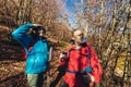 Couple travellers hiking in nature, walking and talking along forest path together drinking hot tea