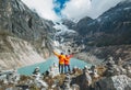 Couple trekkers dressed bright jackets on the rock enjoying a glacier falling in high altitude Sabai Tso glacial lake cca 4350m.