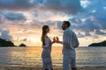 Couple in tropical vacation with drinks toasting on beach by the sea