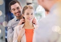 Couple trying golden pendant on at jewelry store