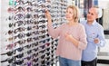 Couple trying spectacles frames and smiling near stand Royalty Free Stock Photo