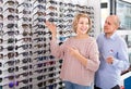 Couple trying spectacles frames and smiling near stand Royalty Free Stock Photo