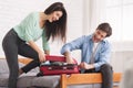 Couple trying to close full suitcase in bedroom