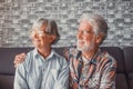 Couple of two beautiful and cute seniors at home sitting on the sofa looking at the window wearing glasses together Royalty Free Stock Photo