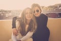 Couple of two beautiful models females hugging outdoor on the rooftop terrace at home. sunset time and sunlight with backlight, Royalty Free Stock Photo