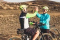 Couple of two caucasian seniors bumped and giving five together - riding their bikes - healthy and fitness lifestyle and concept