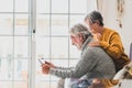 Couple of two cheerful and happy mature and old people seniors using tablet and having fun sitting on the sofa at home together.