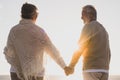 Couple of two happy and active seniors having fun and enjoying together summer at the beach walking holding their hands with the Royalty Free Stock Photo