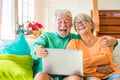 Couple of two happy mature and old people or seniors at home sitting on the sofa enjoying and having fun laughing together looking