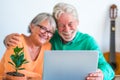 Couple of two happy mature and old people or seniors at home sitting on the sofa enjoying and having fun together looking and Royalty Free Stock Photo