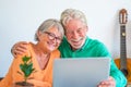 Couple of two happy mature and old people or seniors at home sitting on the sofa enjoying and having fun together looking and Royalty Free Stock Photo