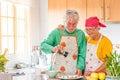 Couple of two happy seniors having fun and cooking together in the kitchen of their home - preparing some healthy food with Royalty Free Stock Photo