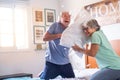 Couple of two happy seniors having fun playing together on the bed at home fighting with pillows enjoying - pillows war indoors in Royalty Free Stock Photo