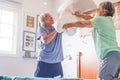 Couple of two happy seniors having fun playing together on the bed at home fighting with pillows enjoying - pillows war indoors in Royalty Free Stock Photo