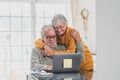 Couple of two happy seniors working and using laptop together at home smiling and having fun together - lockdown lifestyle Royalty Free Stock Photo