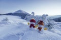 Couple two little snowmen in red hat and scarf on snowy field. Beautiful winter sunset background. Landscape with high mountains.