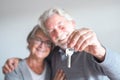 Couple of two seniors after buy a new house or car and go to live together - man holding a key and mature man and woman looking at Royalty Free Stock Photo