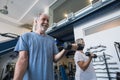 Couple of two seniors and mature people at the gym doing exercise - adults holding a dumbbell and working biceps together