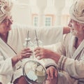 Couple of two seniors in a resort or hotel drinking a cocktail and clincking - pensioners relaxed with a beauty treatment Royalty Free Stock Photo